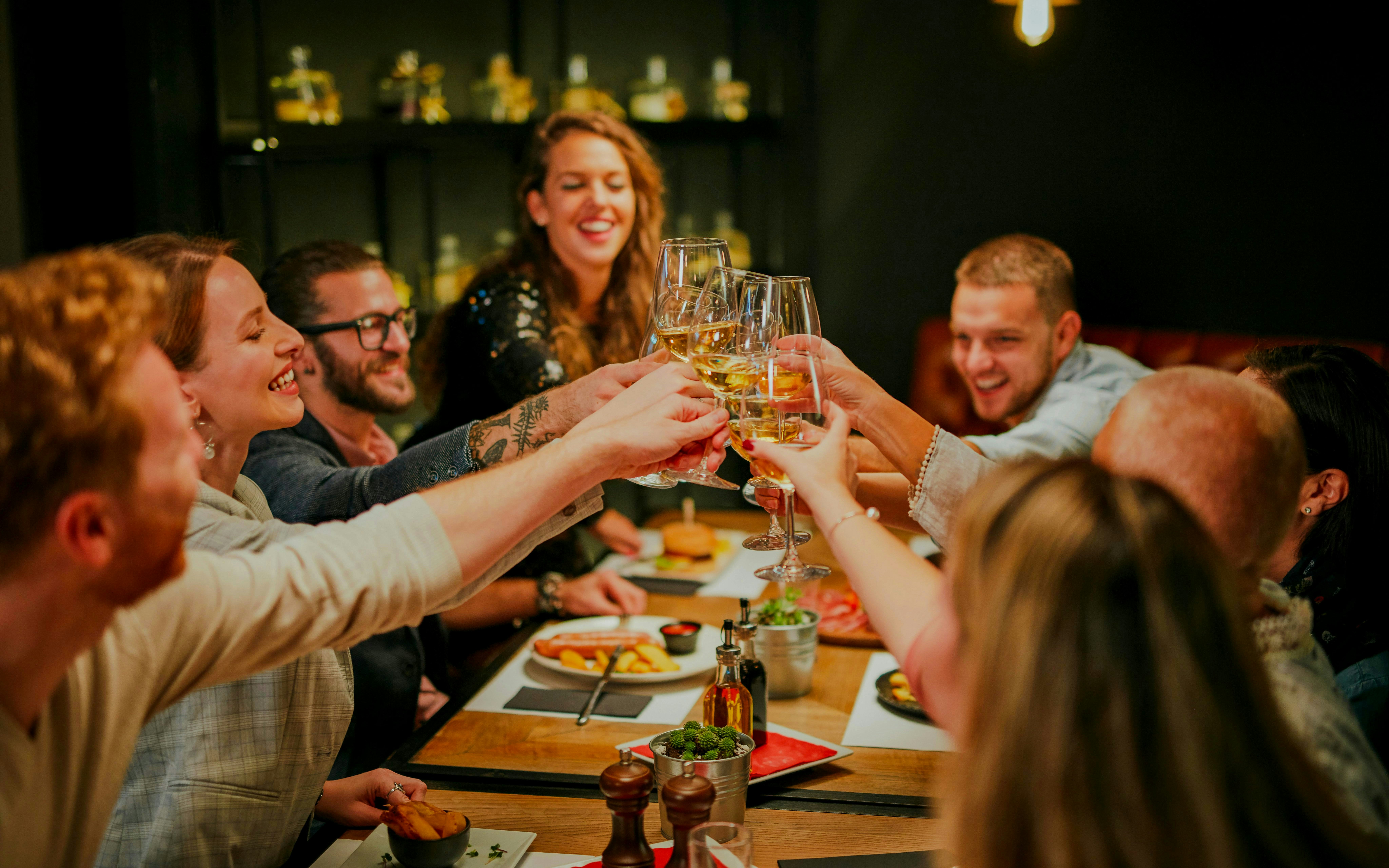 Friends toasting with white wine at a restaurant dinner.