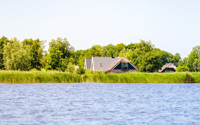 Giethoorn canal view with traditional houses and lush greenery.