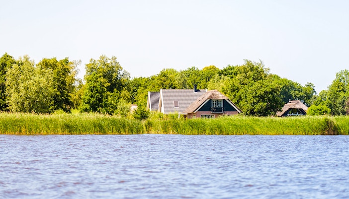 Giethoorn canal view with traditional houses and lush greenery.
