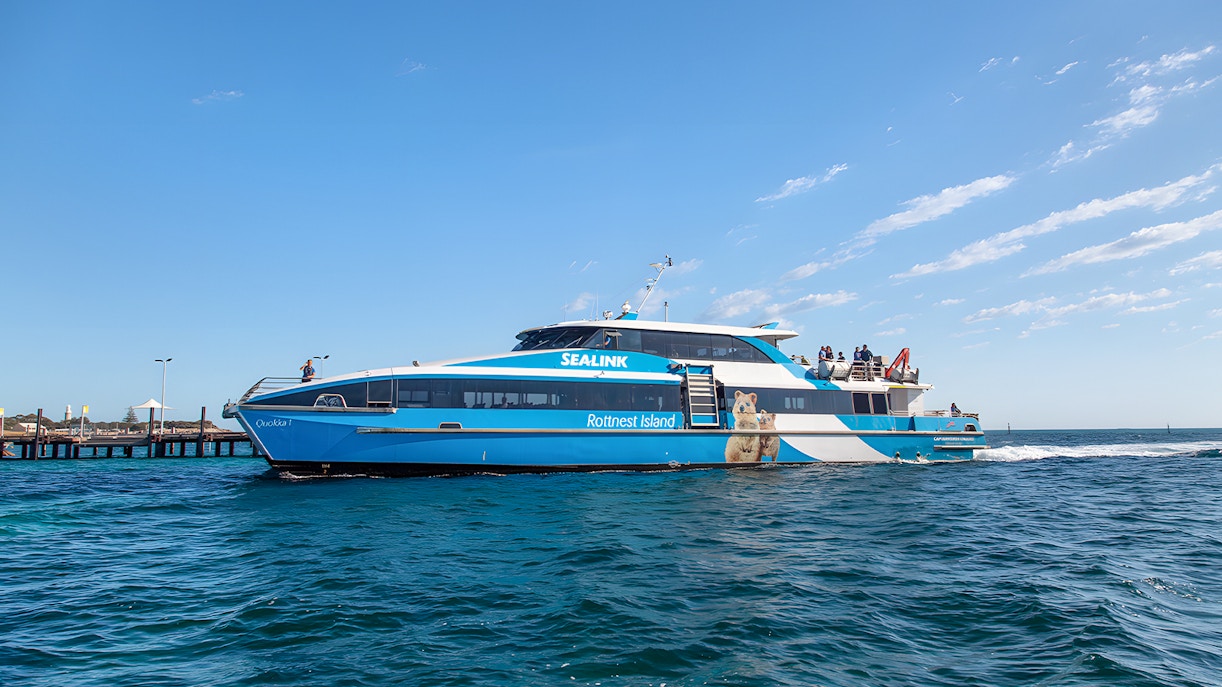 Group of tourists enjoying a sunny day on the Rottnest Island Guided Bus Tour with Return Ferry from Perth or Fremantle, with a view of the island's unique landscape and wildlife.