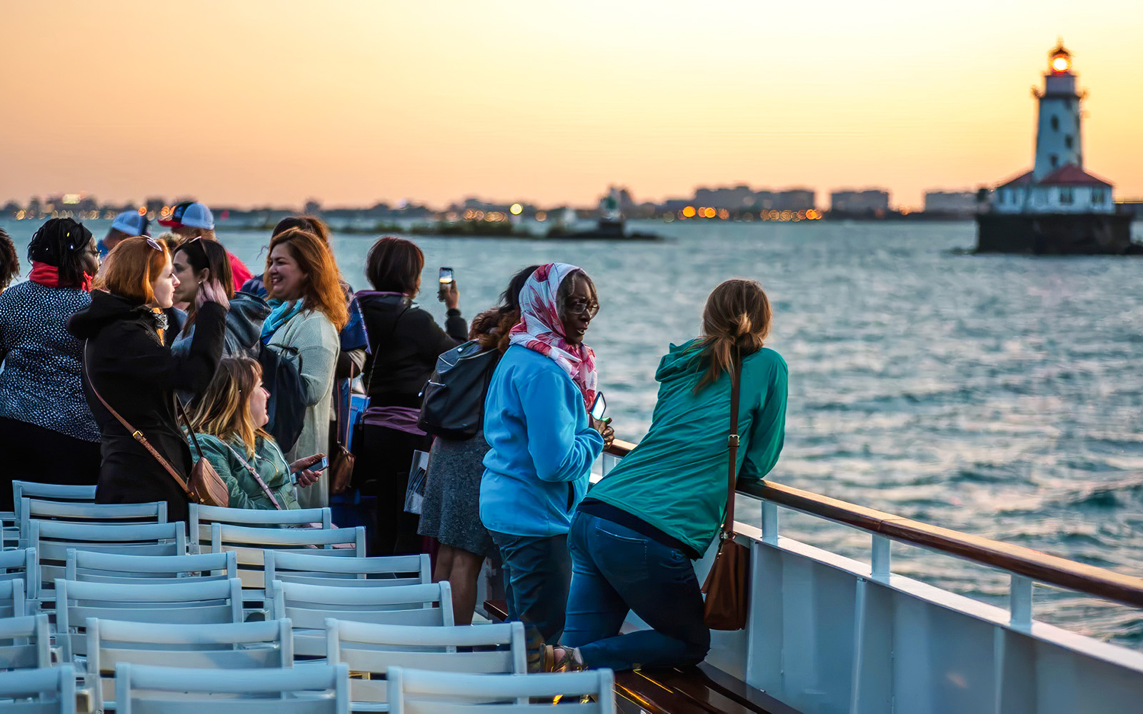 Group enjoying a sunset cruise on Lake Michigan with Chicago lighthouse in view.