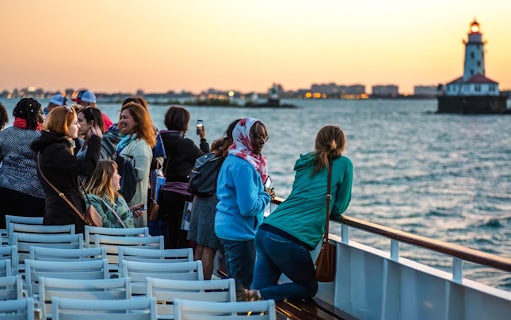 Group enjoying a sunset cruise on Lake Michigan with Chicago lighthouse in view.