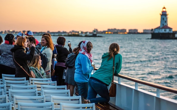 Group enjoying a sunset cruise on Lake Michigan with Chicago lighthouse in view.