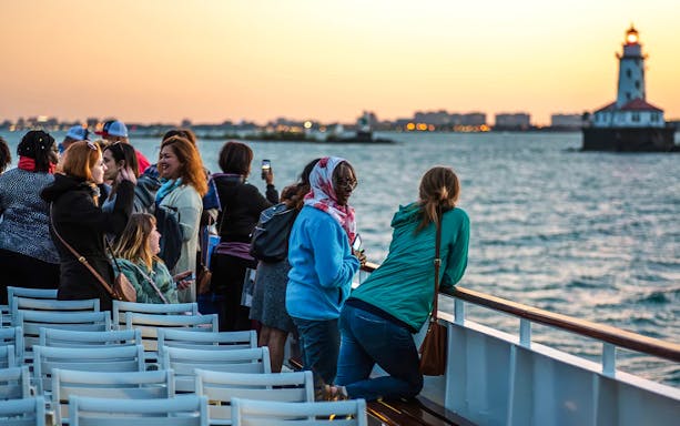Group enjoying a sunset cruise on Lake Michigan with Chicago lighthouse in view.