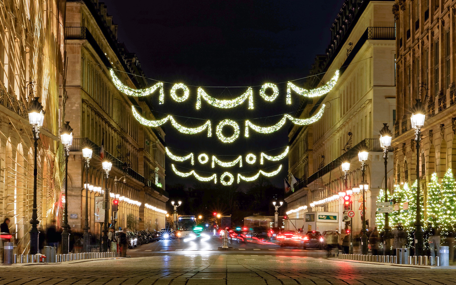 Paris street adorned with Christmas lights at night.