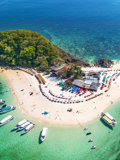Aerial view of Khai Island, Thailand, with boats, beach umbrellas, and lush greenery.