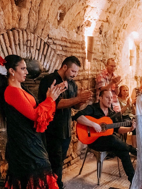 Flamenco dancer performing at Tablao Arab Baths of Santa María with audience watching.