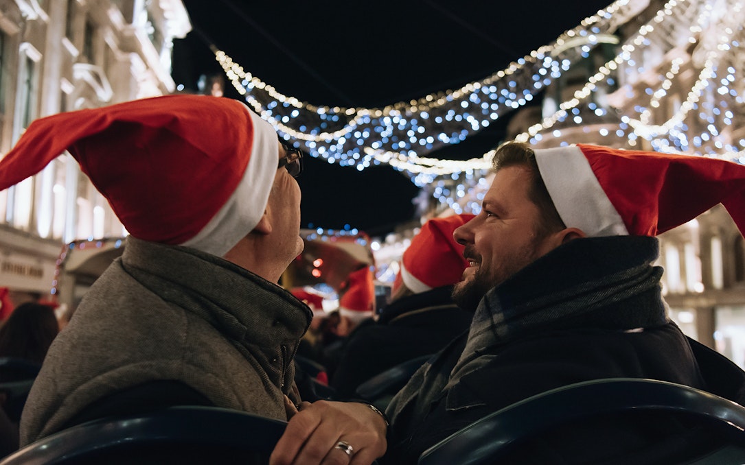 People wearing Santa hats on a Tootbus tour viewing London Christmas lights.