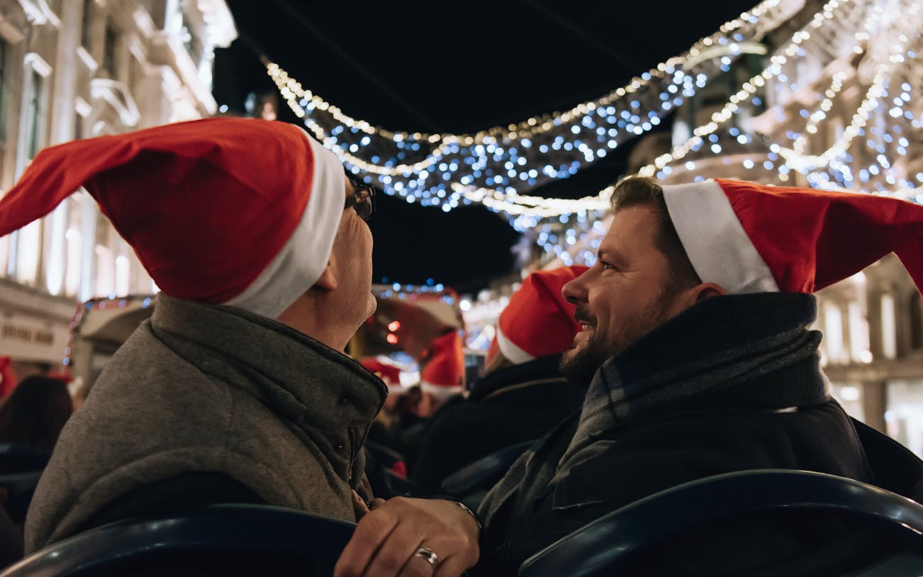 People wearing Santa hats on a Tootbus tour viewing London Christmas lights.