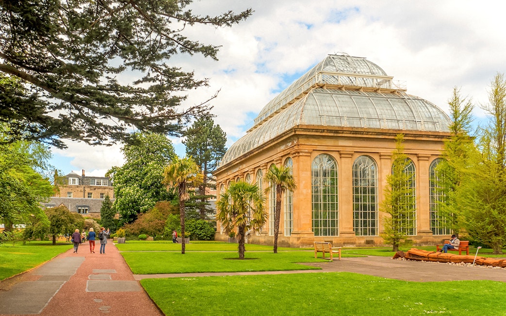 Edinburgh Botanic Garden glasshouse with visitors walking nearby.