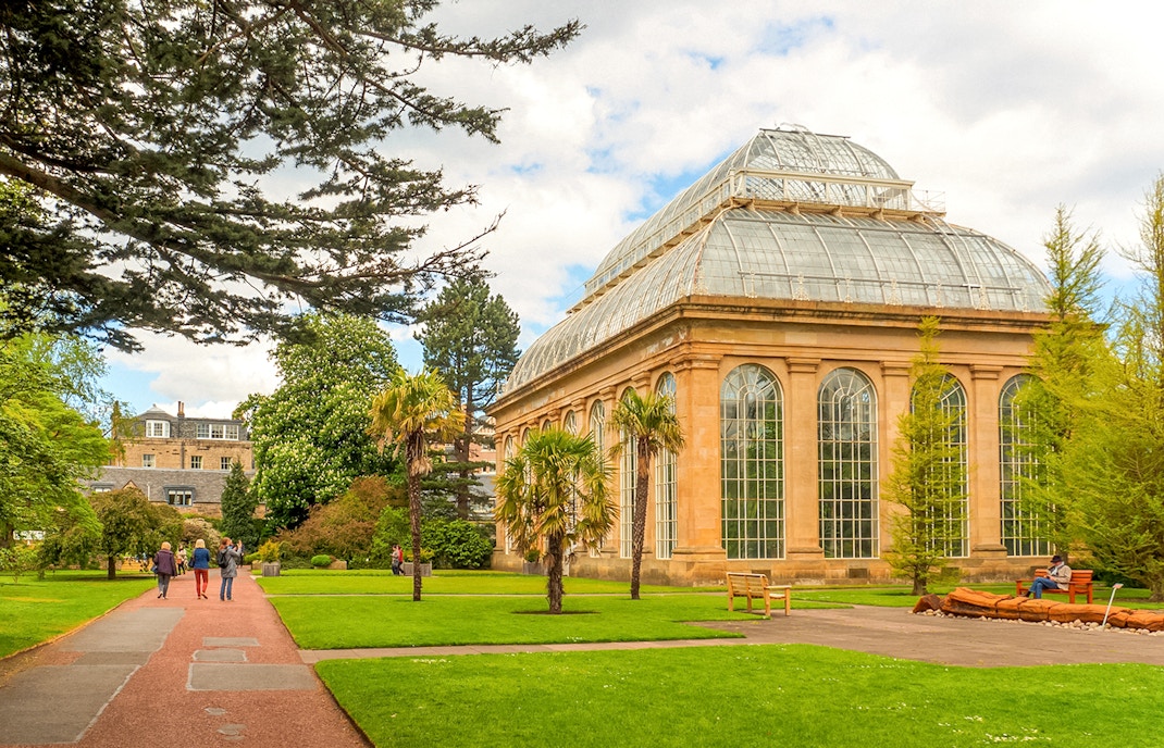 Edinburgh Botanic Garden glasshouse with visitors walking nearby.