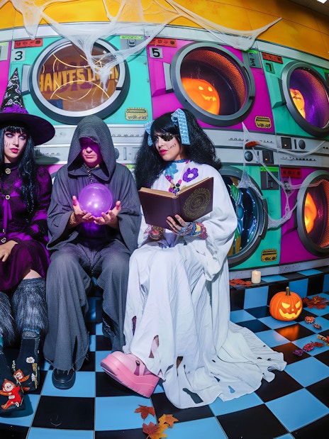 People in Halloween costumes at Enchanted Carnival, House of Hype, with pumpkins and colorful backdrop.