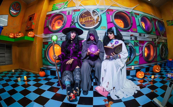 People in Halloween costumes at Enchanted Carnival, House of Hype, with pumpkins and colorful backdrop.