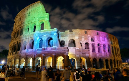 Colosseum illuminated with colorful lights at night, Rome, Italy.