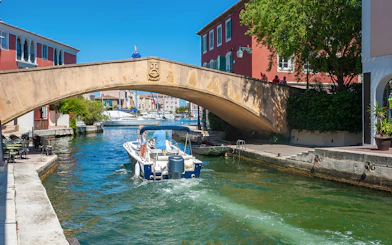 Boat passing under a stone bridge in Port Grimaud during St Tropez sightseeing tour.