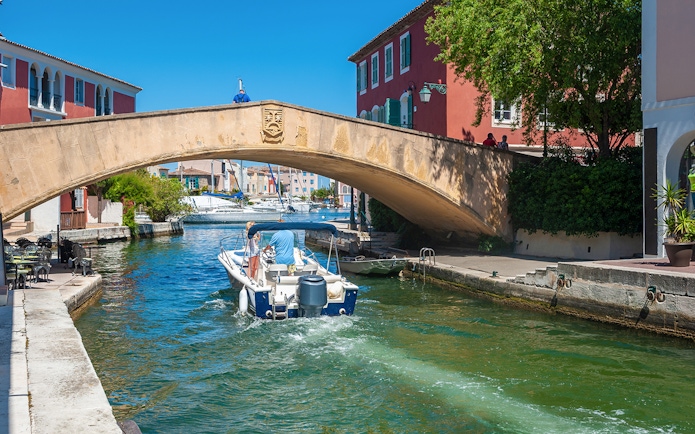 Boat passing under a stone bridge in Port Grimaud during St Tropez sightseeing tour.