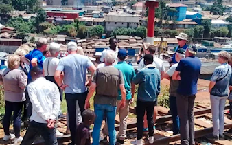 Tour group overlooking Kibera Slum in Nairobi with a guide explaining the area.