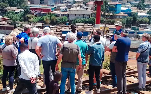 Tour group overlooking Kibera Slum in Nairobi with a guide explaining the area.