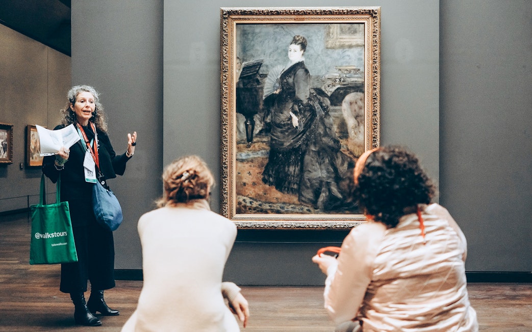 Guide explaining painting to tourists inside Orsay Museum, Paris.