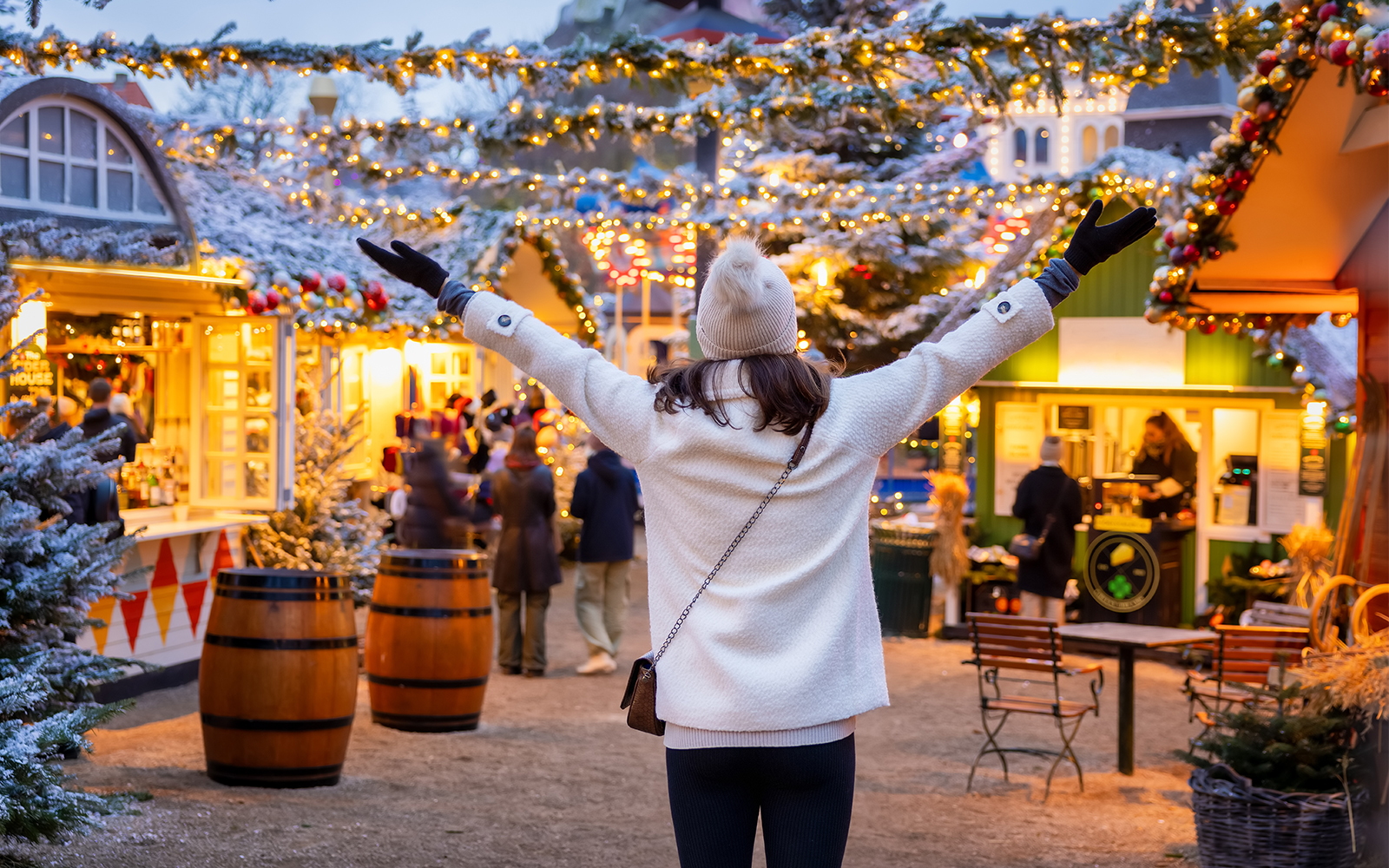 Person enjoying a festive Christmas market with lights and decorated stalls.
