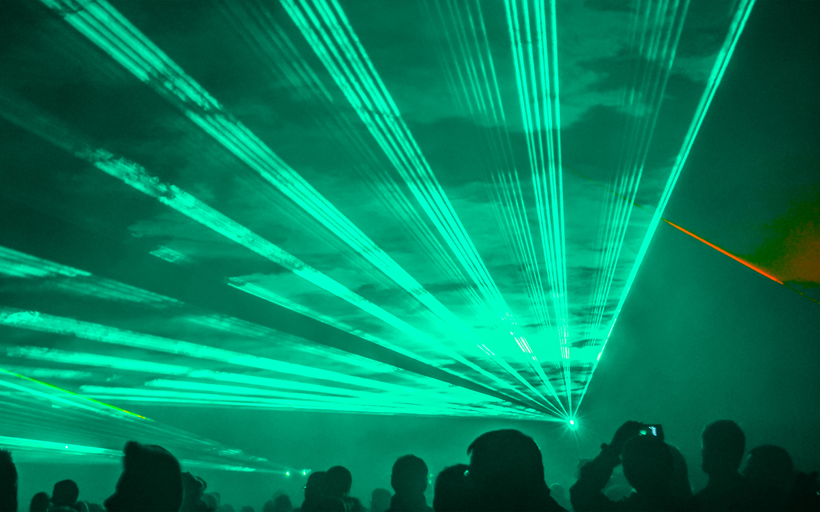 Crowd watching a vibrant green laser show at night.