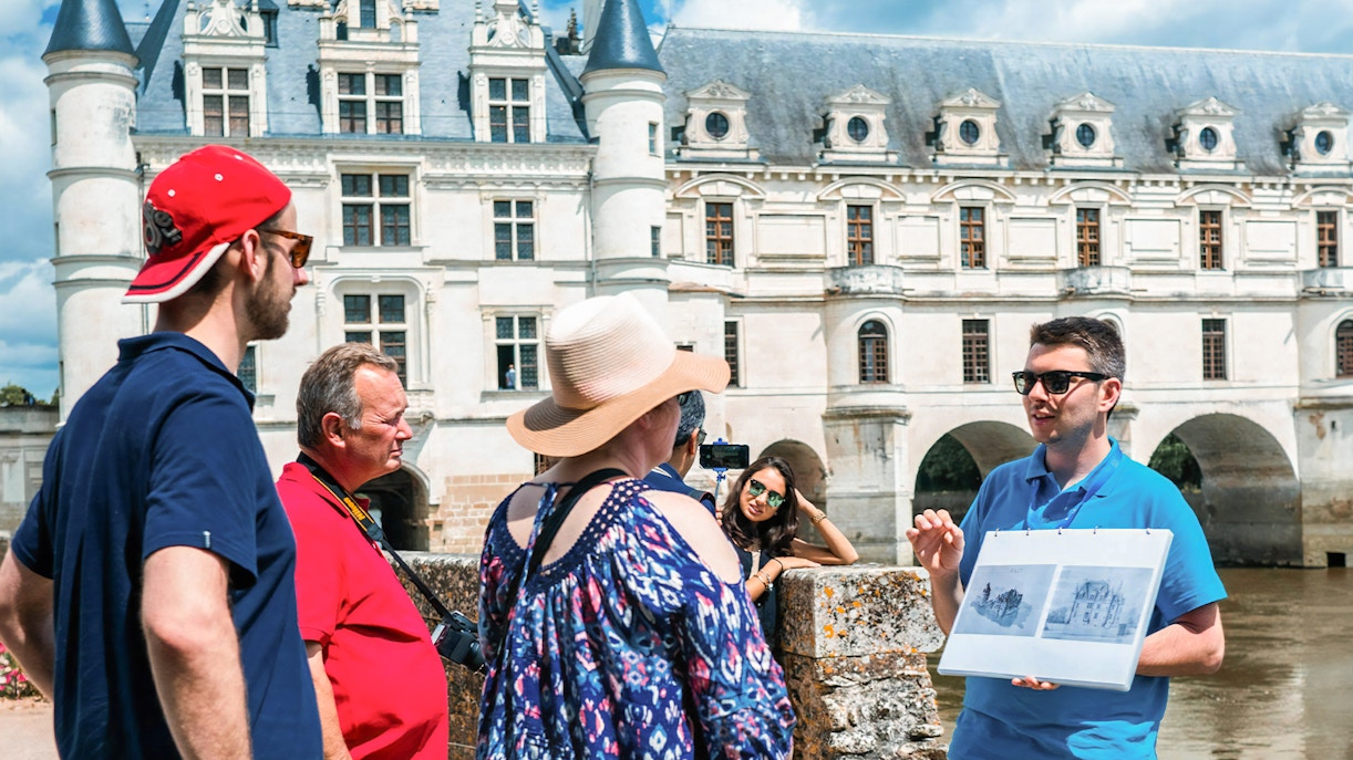 Guide explaining Chenonceau Castle to tour group in Loire Valley.