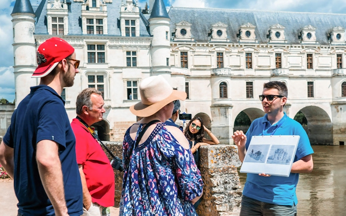 Guide explaining Chenonceau Castle to tour group in Loire Valley.