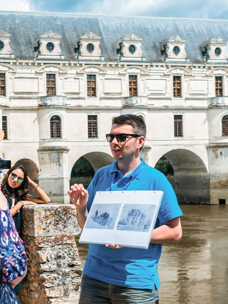 Guide explaining Chenonceau Castle to tour group in Loire Valley.