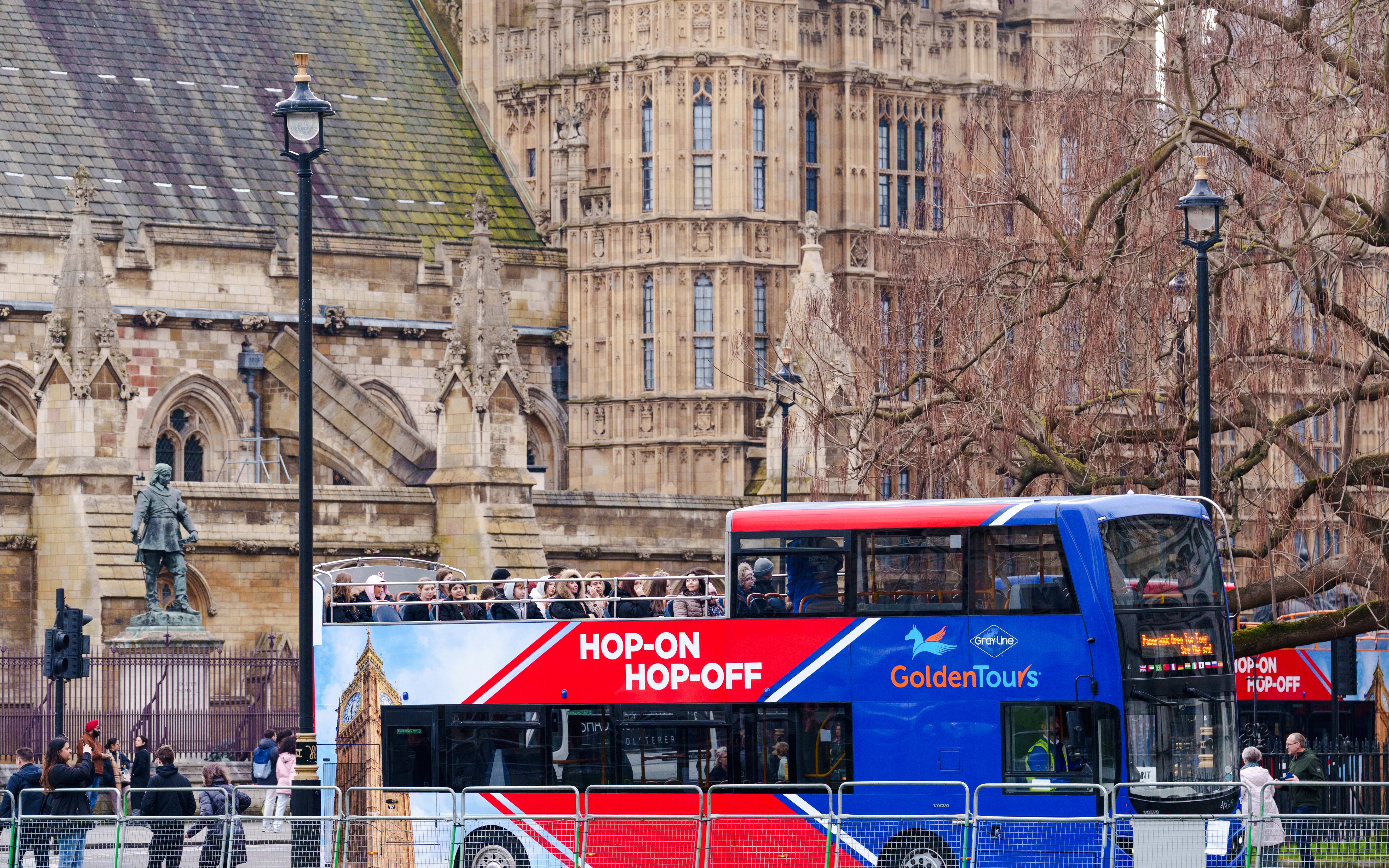 Golden Tours hop-on hop-off bus in front of historic London architecture.