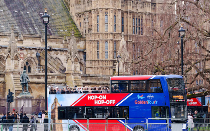 Golden Tours hop-on hop-off bus in front of historic London architecture.
