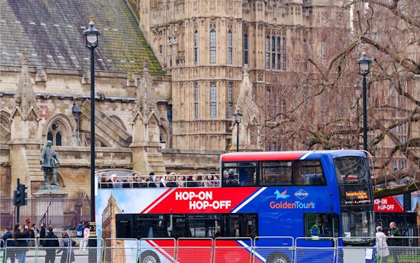 Golden Tours hop-on hop-off bus in front of historic London architecture.