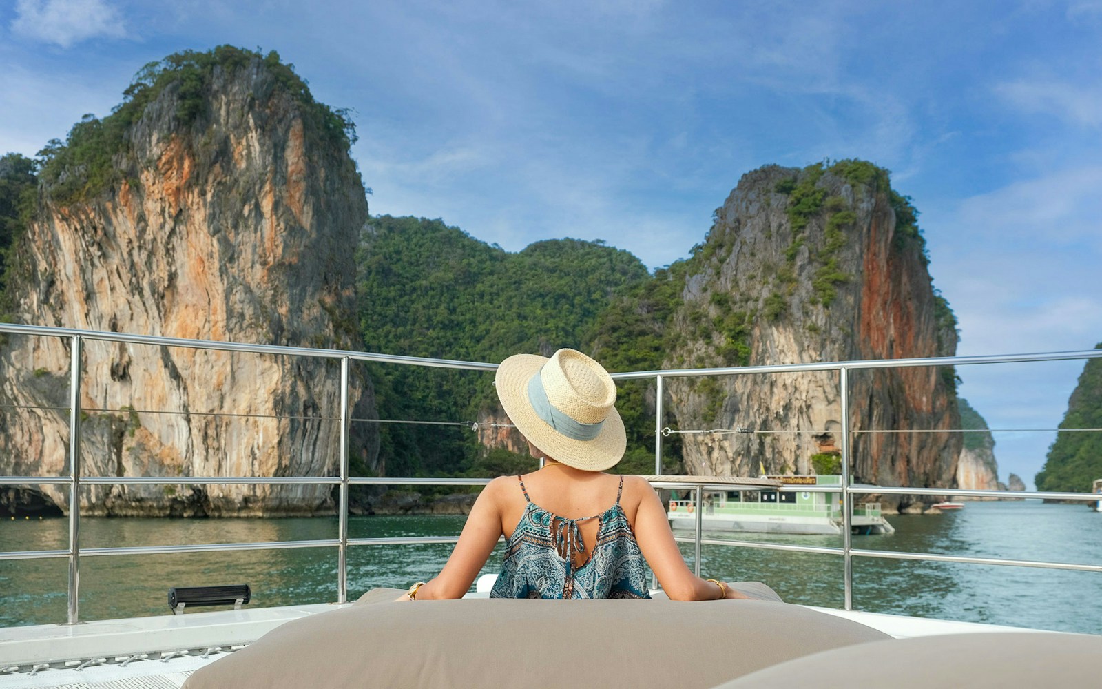 Person relaxing on a yacht with view of limestone cliffs in Phang Nga Bay, Thailand.