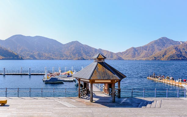 Pier and gazebo at Chuzenji Lake in Nikko with mountains in the background.