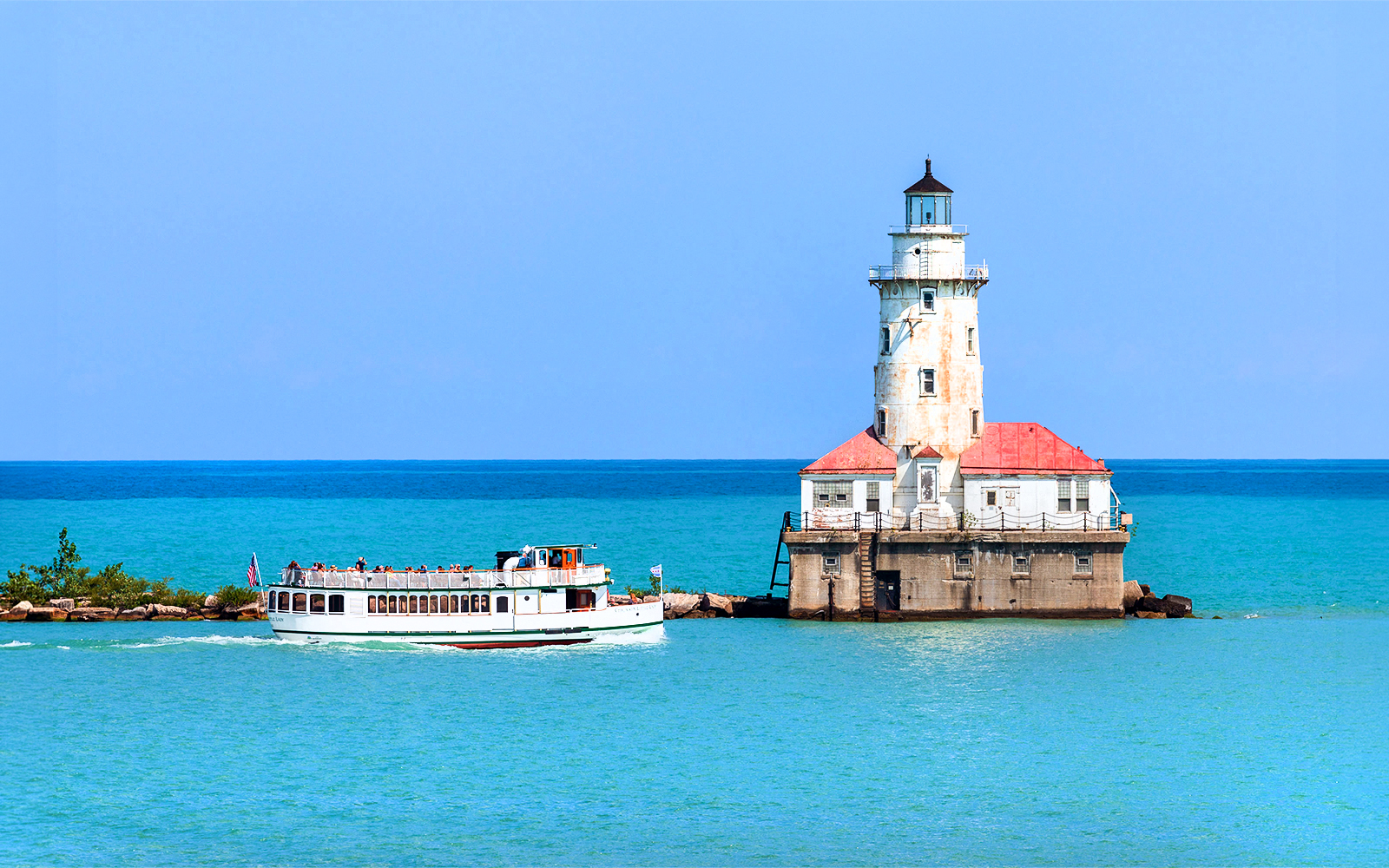 Cruise boat near Chicago Harbor Lighthouse on Lake Michigan.
