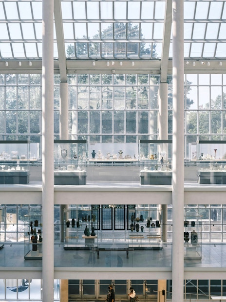 Interior view of the Metropolitan Museum of Art, New York, showcasing glass display cases and visitors.