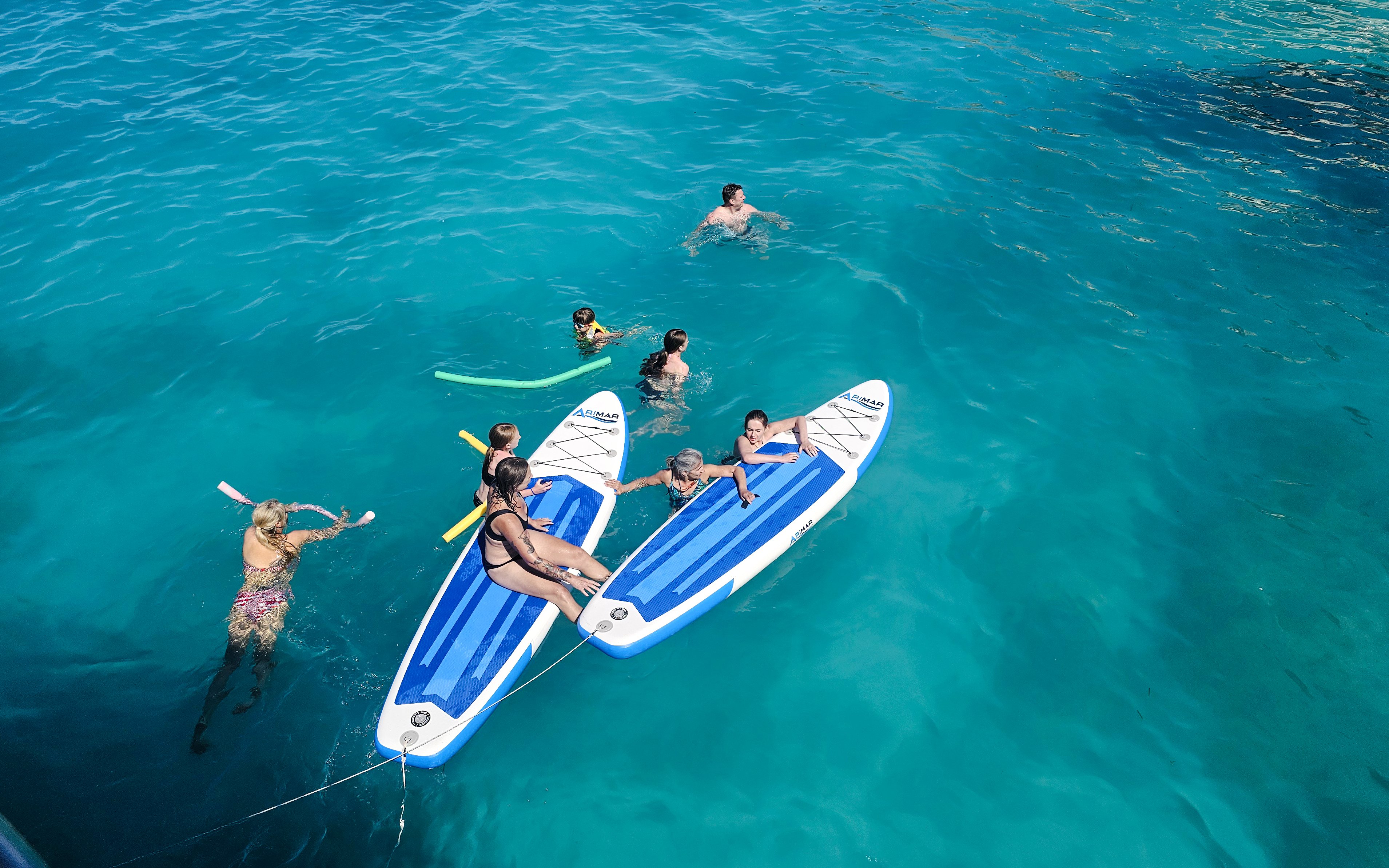 People enjoying paddleboarding and swimming in clear blue waters on a Dreamy Cruise, Kefalonia.