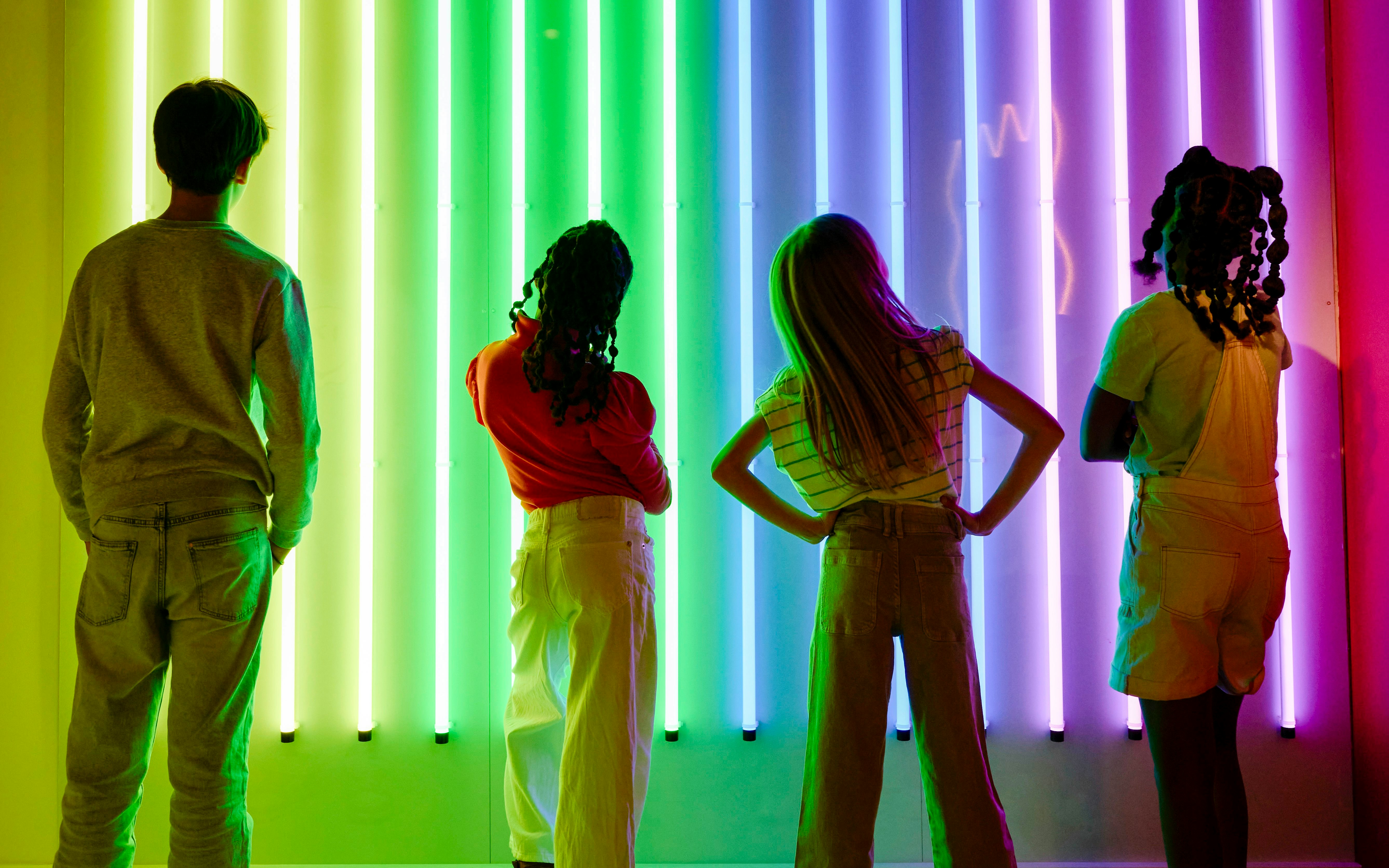 Guests viewing neon light display at Twist Museum, London.