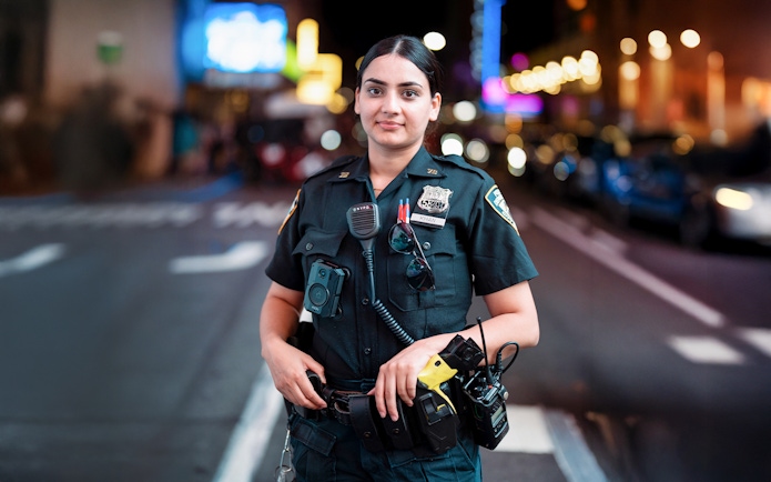 NYPD officer standing in Times Square, NYC at night.