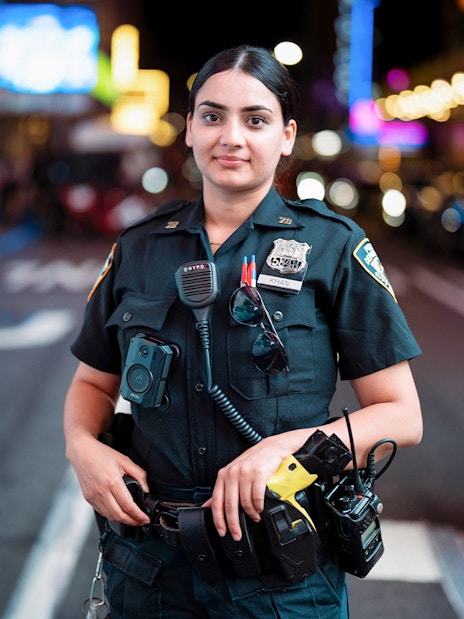 NYPD officer standing in Times Square, NYC at night.