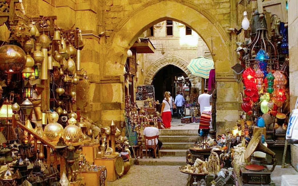 Woman exploring Khan el-Khalili bazaar in Cairo, surrounded by colorful lanterns and traditional crafts.
