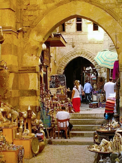 Woman exploring Khan el-Khalili bazaar in Cairo, surrounded by colorful lanterns and traditional crafts.