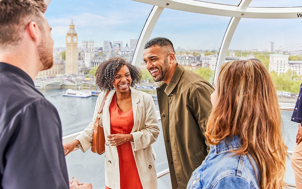 Group enjoying view from London Eye capsule with Big Ben in background.