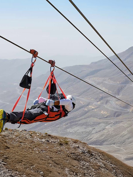 Person ziplining over Jebel Jais mountains in Ras Al Khaimah, UAE.