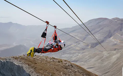 Person ziplining over Jebel Jais mountains in Ras Al Khaimah, UAE.
