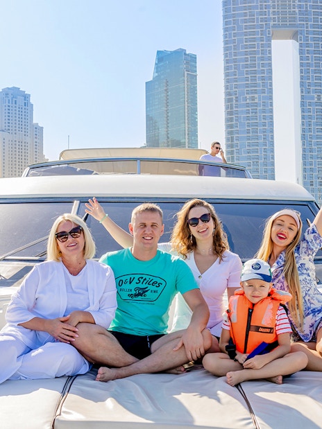 Tourists enjoying a yacht tour with Dubai skyline in the background.