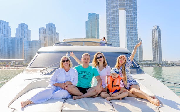Tourists enjoying a yacht tour with Dubai skyline in the background.