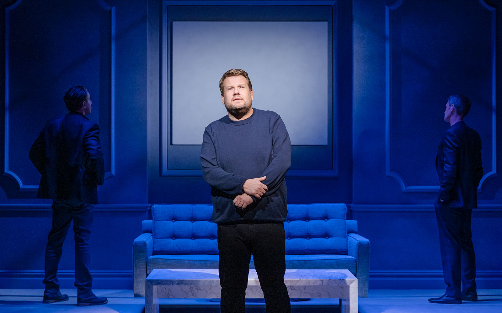 Stage performance of Art Broadway show with actor in front of blue set.