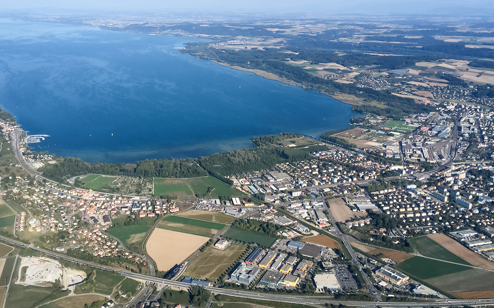 Aerial view of Bernese Seeland and Jura landscape with lake and town.