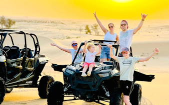Group enjoying dune buggy ride during evening desert safari in Abu Dhabi.