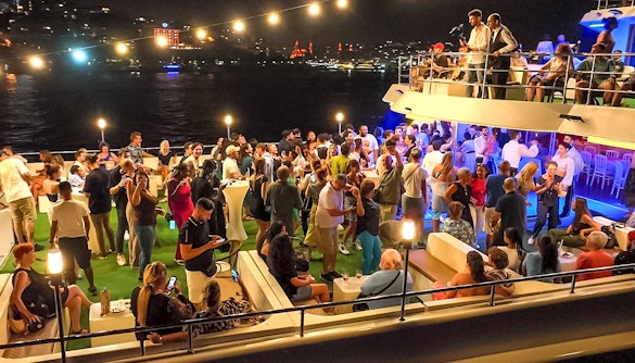 Bosphorus dinner cruise with guests enjoying a Turkish show on a private table under city lights.